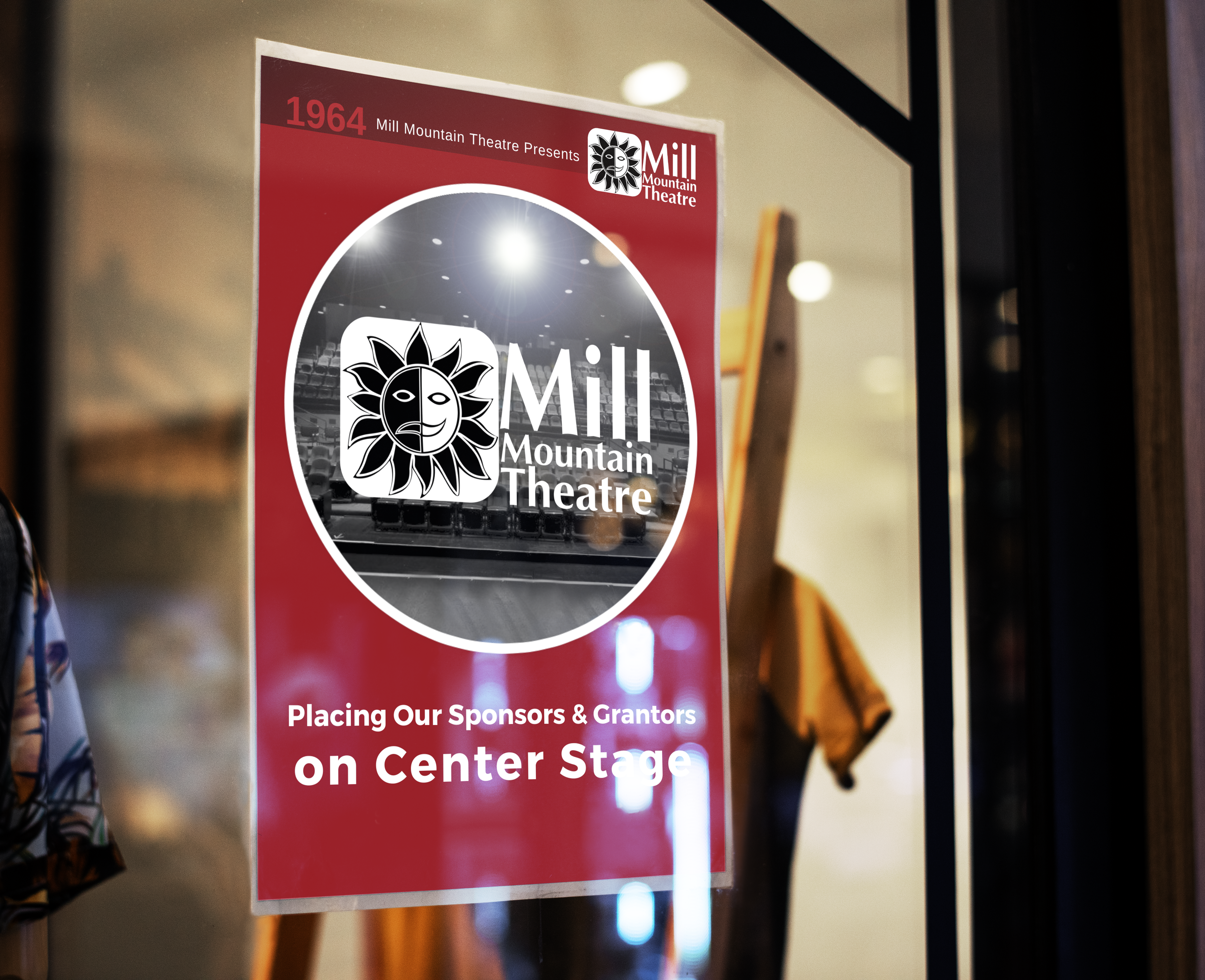 Window with a red poster placed on top. Poster reads Mill Mountain Theatre. Subtitle says Placing our Sponsors and Grantors on Center Stage